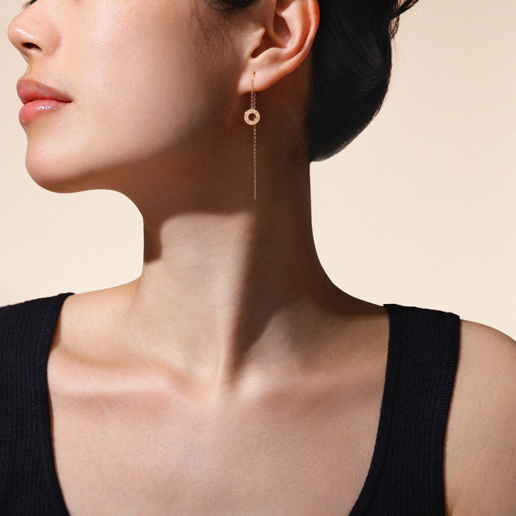 Close-up of a woman wearing a rose gold earrings against a neutral background.