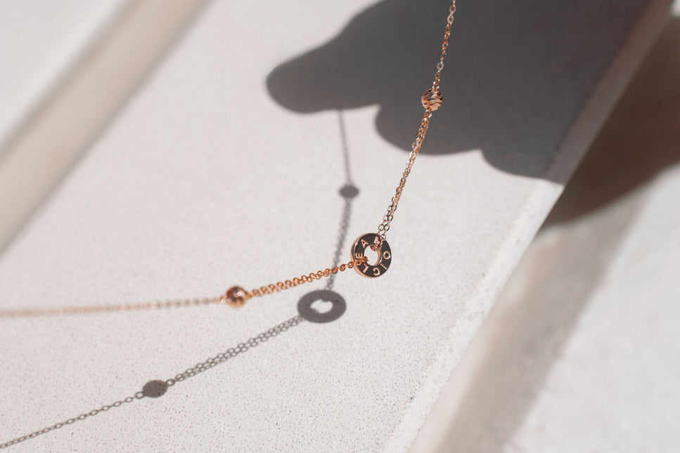 A close up of the Just Cléamoi Necklace on a white stone background