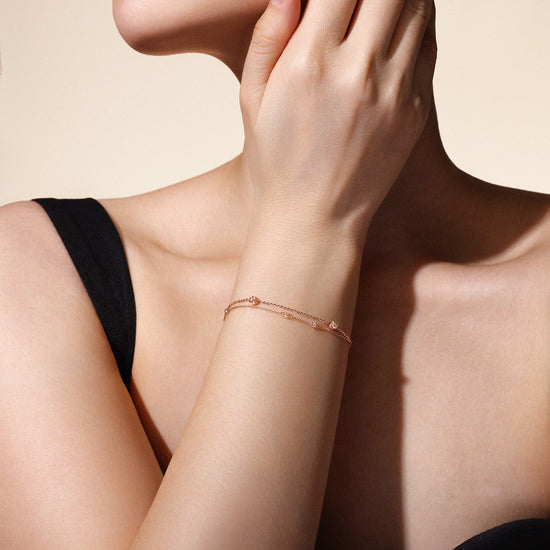 Woman's arm wearing a rose gold bracelet against a neutral background