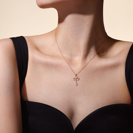 Rose gold necklace with a unique pendant on a model wearing a black top against a beige background