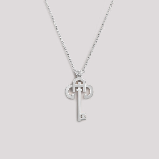 A white gold necklace with a key-shaped pendant, featuring a diamond at the top of the key.