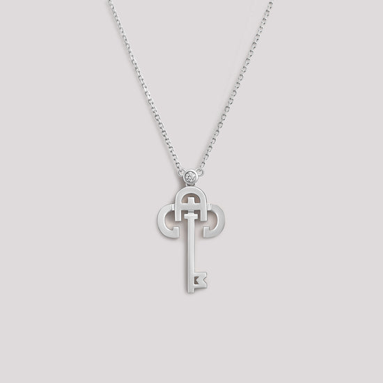 A white gold necklace with a key-shaped pendant, featuring a diamond at the top of the key.