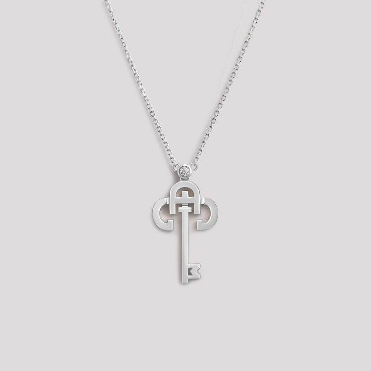 A white gold necklace with a key-shaped pendant, featuring a diamond at the top of the key.