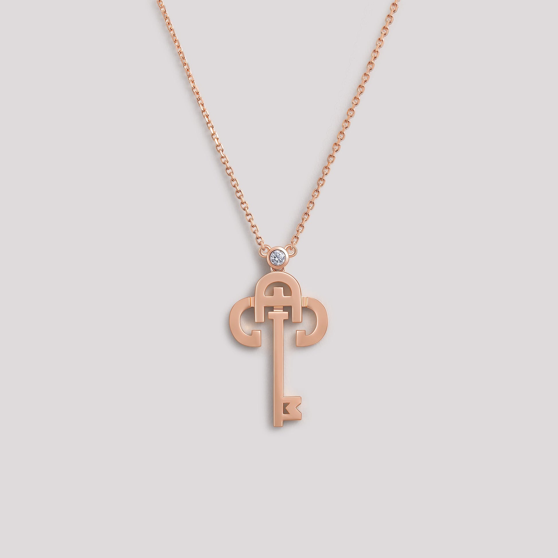 A gold necklace with a key-shaped pendant, featuring a diamond at the top of the key.