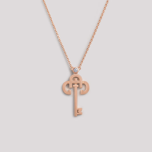 A gold necklace with a key-shaped pendant, featuring a diamond at the top of the key.