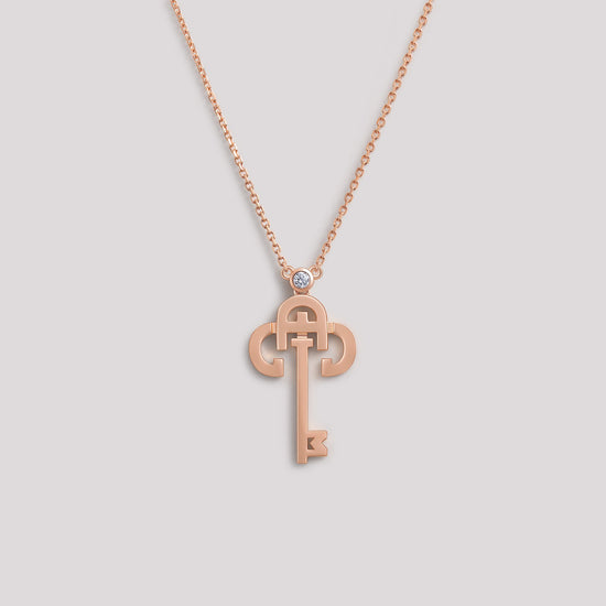 A gold necklace with a key-shaped pendant, featuring a diamond at the top of the key.