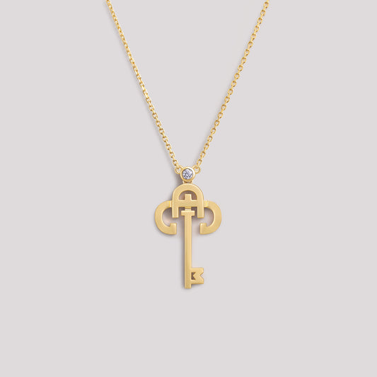 A yellow gold necklace with a key-shaped pendant, featuring a diamond at the top of the key.