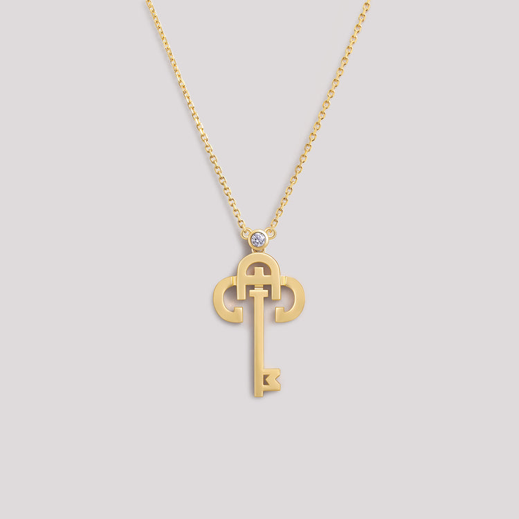 A yellow gold necklace with a key-shaped pendant, featuring a diamond at the top of the key.