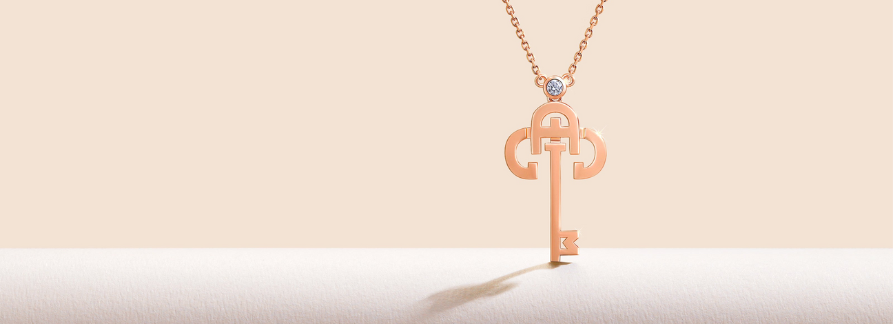 Rose gold key-shaped pendant on a light pink background