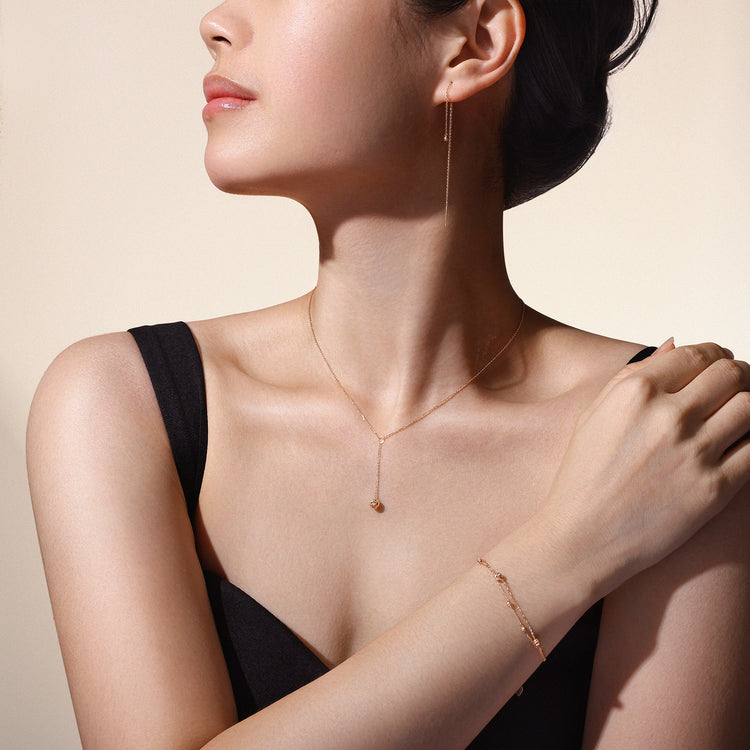 Model wearing matching Joy Collection necklace, bracelet and earrings crafted in solid 18k (750) rose gold.